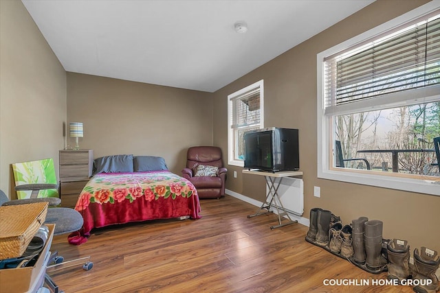 bedroom with radiator, baseboards, and wood finished floors