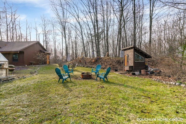 view of yard featuring an outdoor structure and an outdoor fire pit