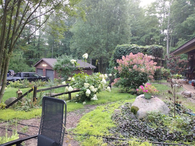 view of yard featuring an outbuilding, a view of trees, and a garage