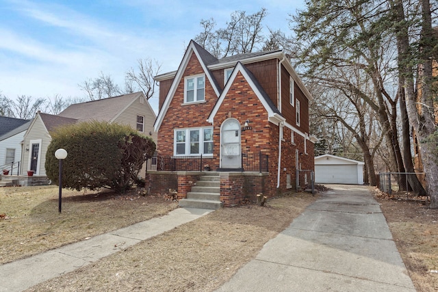 tudor house with brick siding, a garage, an outdoor structure, and roof with shingles