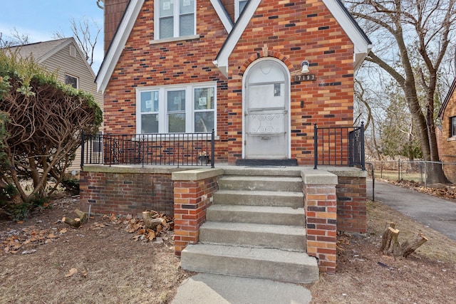 view of front of home featuring aphalt driveway, fence, and brick siding