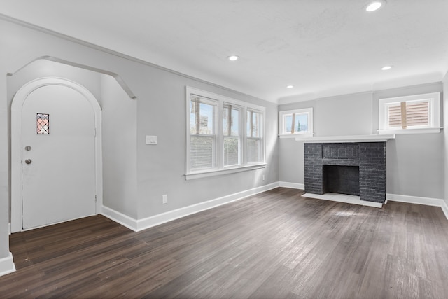 unfurnished living room with dark wood-style floors, recessed lighting, a brick fireplace, and baseboards