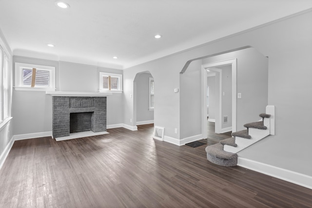 unfurnished living room featuring arched walkways, recessed lighting, baseboards, and wood finished floors