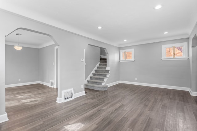 interior space with visible vents, dark wood-style floors, arched walkways, baseboards, and stairs