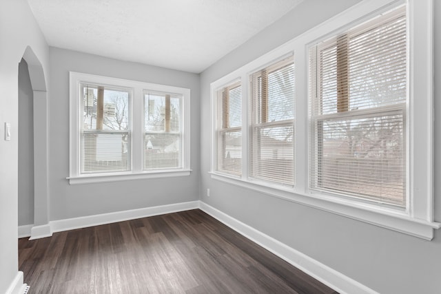 empty room featuring dark wood-style floors, baseboards, and a textured ceiling