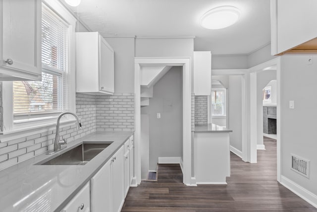 kitchen with visible vents, a fireplace, a sink, dark wood-type flooring, and white cabinetry