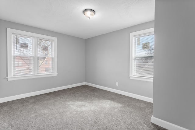 carpeted spare room with baseboards and a textured ceiling