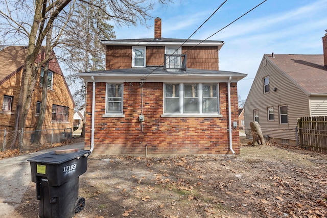 view of front of house with brick siding, a chimney, and fence