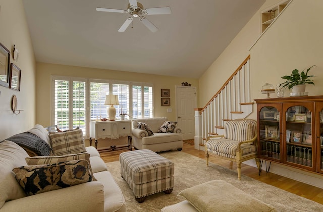 living room with lofted ceiling, a ceiling fan, wood finished floors, and stairs