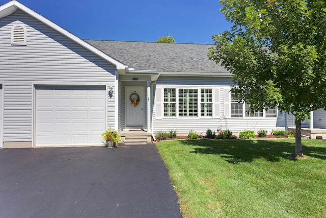 ranch-style house with a front yard, an attached garage, driveway, and roof with shingles