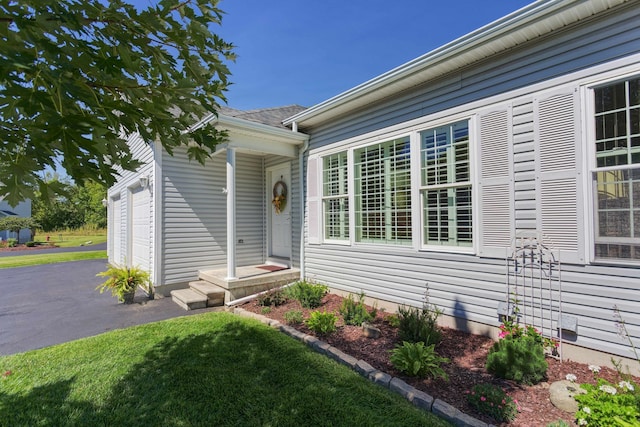 view of exterior entry featuring driveway and a garage