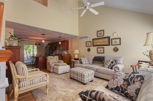 living room featuring a ceiling fan, light wood-style floors, visible vents, and high vaulted ceiling