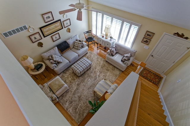 living area featuring ceiling fan, visible vents, baseboards, and wood finished floors