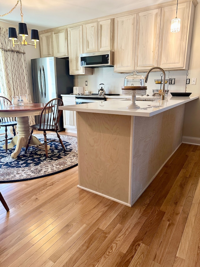 kitchen featuring extractor fan, light countertops, a peninsula, freestanding refrigerator, and light wood-style floors