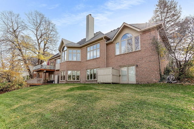 rear view of property with a wooden deck, a yard, brick siding, and a chimney