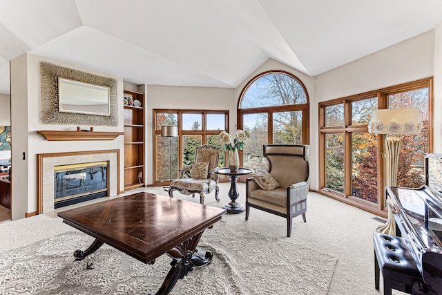 carpeted living area with built in shelves, a fireplace, and vaulted ceiling