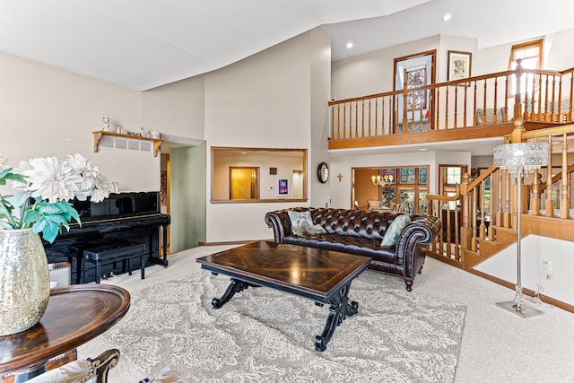 carpeted living area with a towering ceiling, a chandelier, and stairs