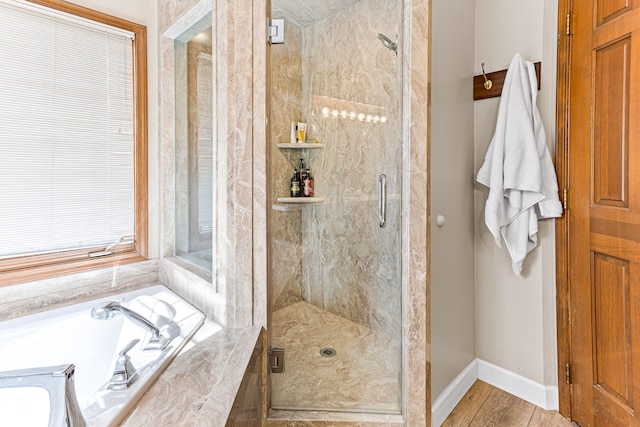 full bathroom featuring a bath, a shower stall, and baseboards