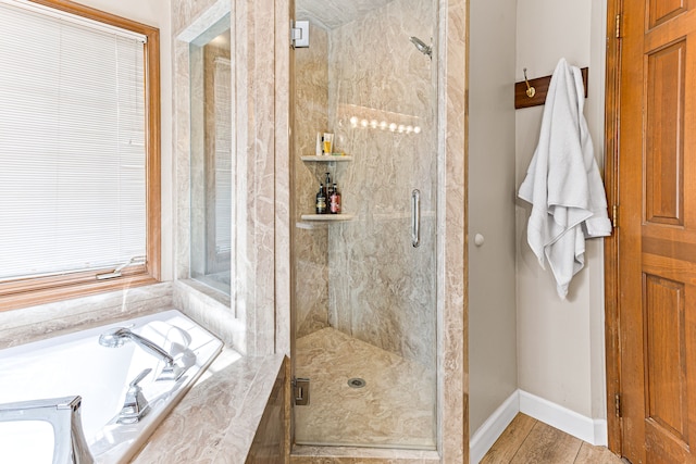 full bath featuring baseboards, a garden tub, and a shower stall