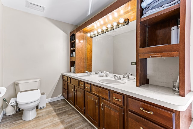 bathroom featuring toilet, wood finished floors, visible vents, and a sink