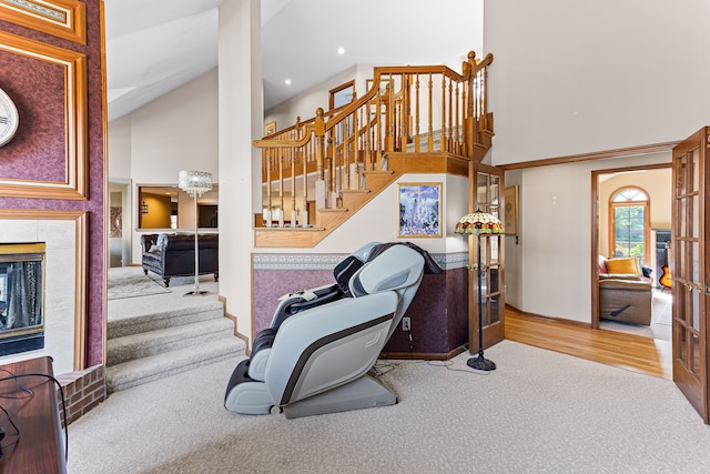staircase featuring high vaulted ceiling, wood finished floors, recessed lighting, carpet floors, and a fireplace
