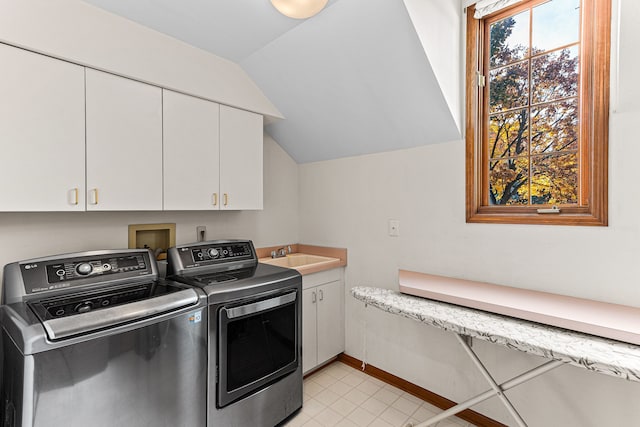 clothes washing area featuring a sink, cabinet space, baseboards, and washing machine and clothes dryer