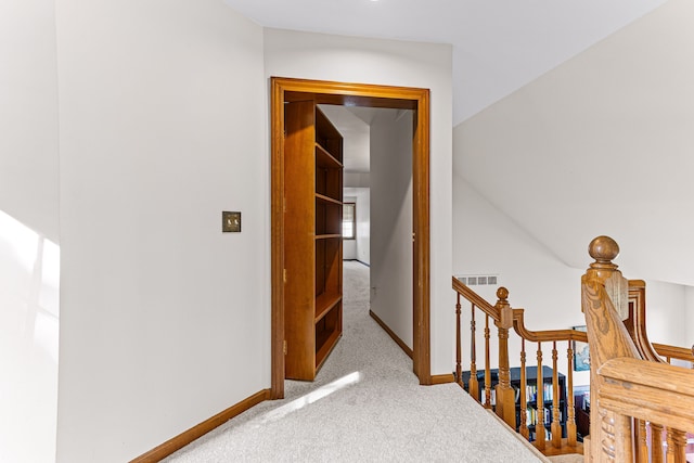 hallway with an upstairs landing, carpet flooring, and baseboards