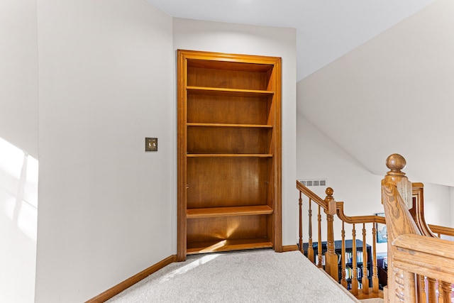 stairs with carpet flooring, baseboards, and built in shelves
