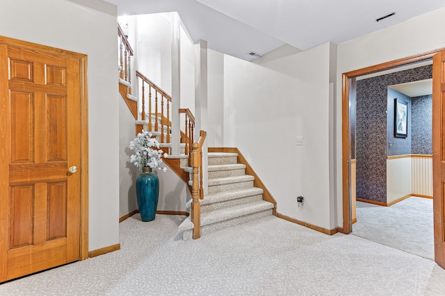 stairway with wallpapered walls, baseboards, and carpet floors