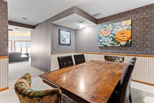 dining area featuring a wainscoted wall, carpet, and wallpapered walls