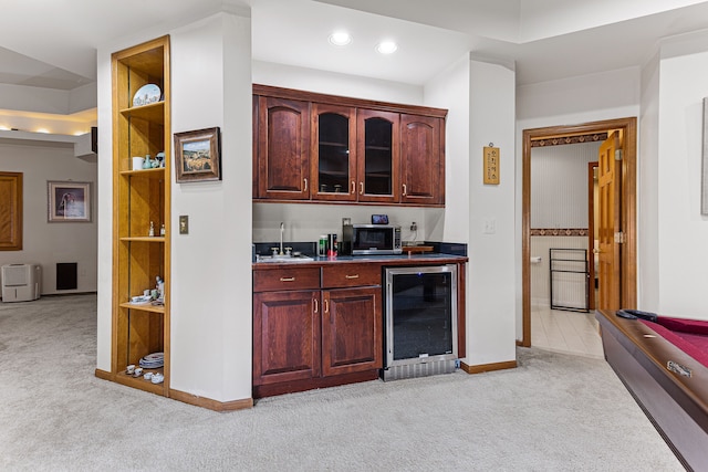 bar with baseboards, a sink, wine cooler, stainless steel microwave, and light colored carpet
