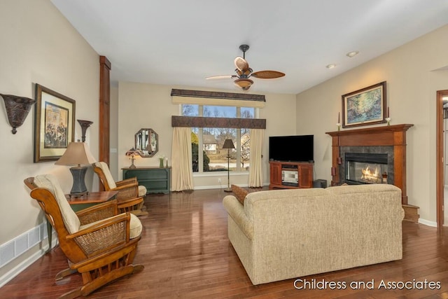 living room with visible vents, a fireplace, baseboards, ceiling fan, and dark wood-style flooring