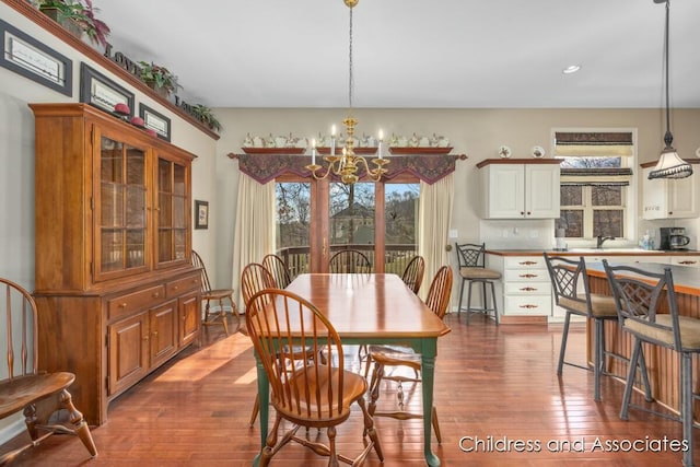 dining area with plenty of natural light, dark wood-type flooring, and an inviting chandelier