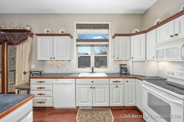 kitchen with a sink, white appliances, dark wood-style flooring, and white cabinetry