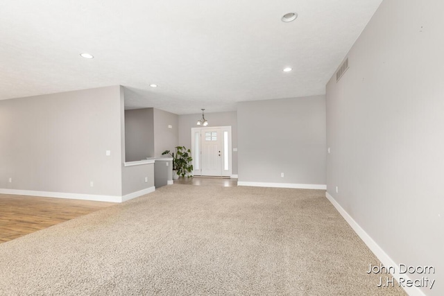 unfurnished living room with light carpet, visible vents, recessed lighting, and baseboards