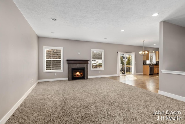 unfurnished living room featuring light colored carpet, a chandelier, and a textured ceiling