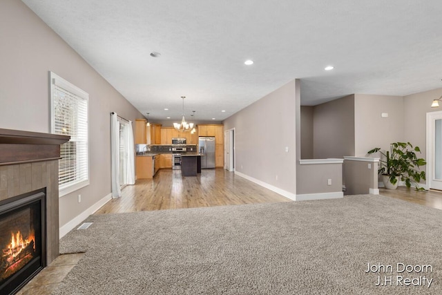 unfurnished living room with recessed lighting, a fireplace, baseboards, and a chandelier