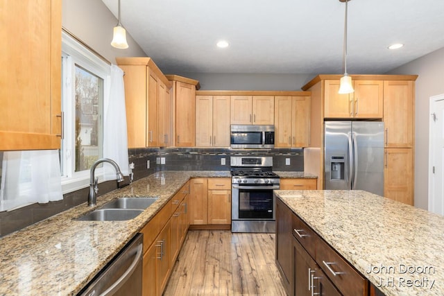 kitchen with light stone countertops, a sink, stainless steel appliances, tasteful backsplash, and light wood-type flooring