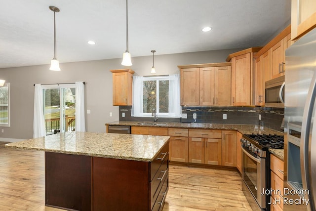 kitchen featuring a sink, a kitchen island, stainless steel appliances, decorative backsplash, and a healthy amount of sunlight