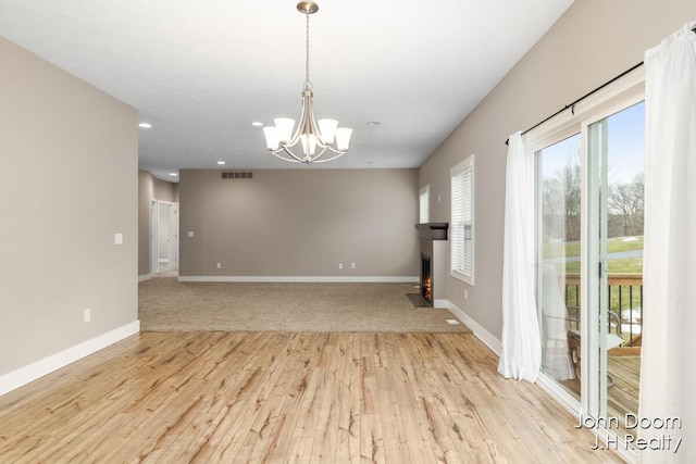 empty room with visible vents, baseboards, an inviting chandelier, and light wood-style flooring