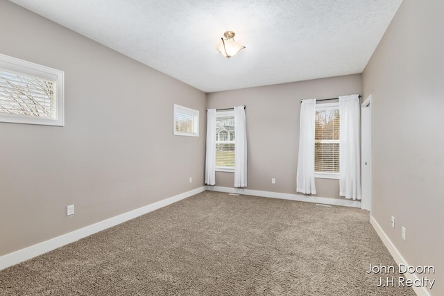 empty room featuring baseboards, carpet, and a textured ceiling