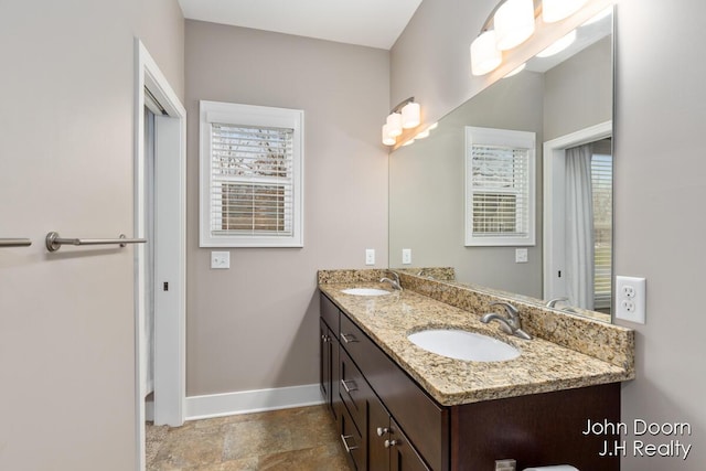 bathroom with double vanity, baseboards, and a sink