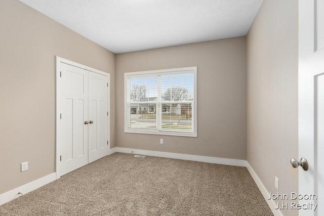 unfurnished bedroom featuring a closet, baseboards, and carpet floors