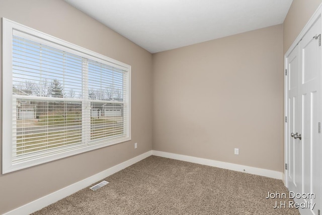 empty room featuring visible vents, baseboards, and carpet