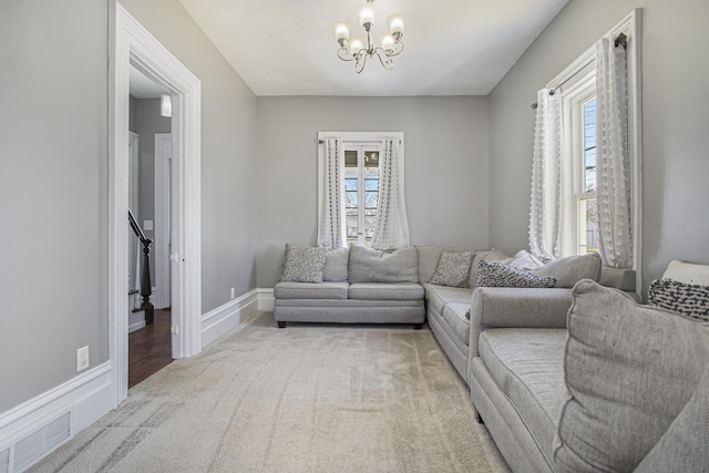 living area with a notable chandelier, visible vents, light carpet, and baseboards