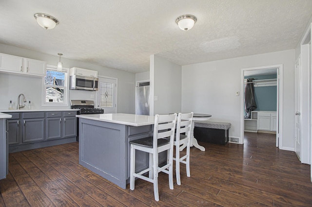 kitchen featuring dark wood-type flooring, gray cabinetry, light countertops, and stainless steel appliances