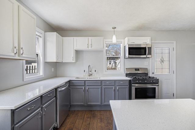 kitchen with gray cabinetry, dark wood-style flooring, appliances with stainless steel finishes, and a sink