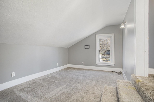 additional living space with baseboards, carpet floors, a textured ceiling, and lofted ceiling