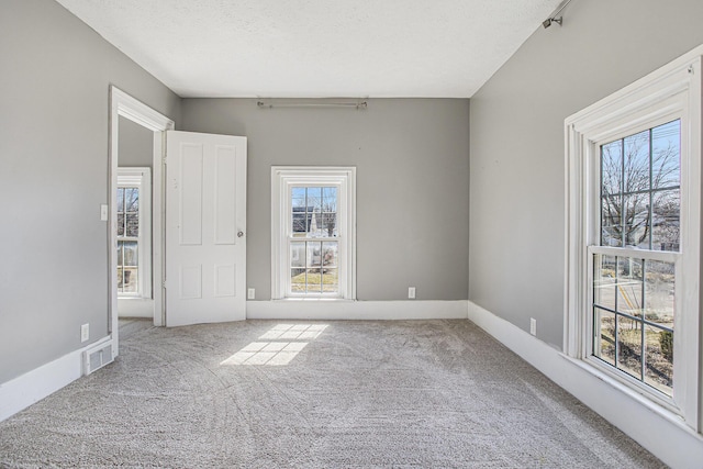 spare room featuring baseboards, carpet, visible vents, and a textured ceiling