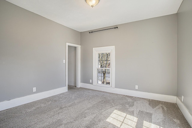 spare room featuring baseboards and light carpet